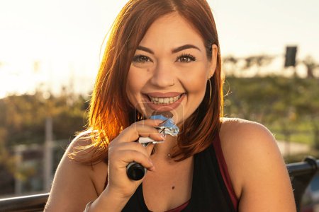 Cheerful woman enjoying a nutritious protein bar after a workout session, with a sunlit park backdrop.