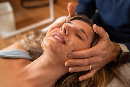 Photo for A woman enjoys a craniosacral therapy session, experiencing relaxation with a gentle head massage. - Royalty Free Image