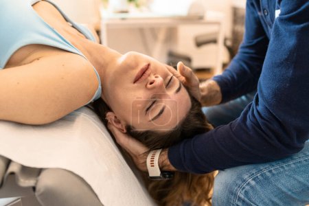 Photo for Osteopath performing a cervical adjustment on a relaxed female patient, enhancing neck mobility and relief. - Royalty Free Image