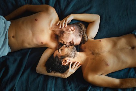 Couple gay partageant un baiser tendre, exprimant amour et connexion dans un cadre serein.