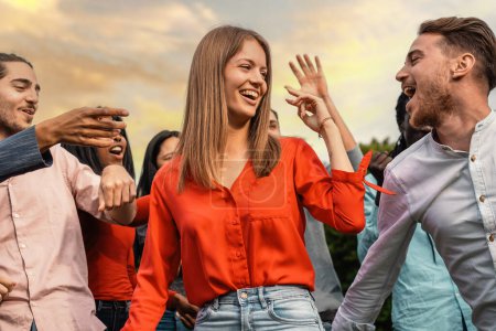 Téléchargez les photos : Groupe d'amis souriants profitant d'une fête en plein air, partageant un moment de bonheur et de convivialité dans un cadre naturel. - en image libre de droit