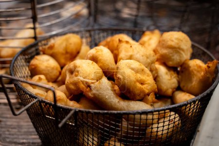 Golden anchovy fritters in a wire basket - Street food delicacy captured at night.