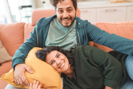 A happy couple shares a cozy and affectionate moment while relaxing on a comfortable couch at home - peaceful and intimate domestic lifestyle - newlywed enjoying the couch, people lifestyle concept.