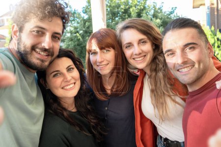 Téléchargez les photos : Jeunes amis partageant un moment de joie en prenant un selfie de groupe - Bonheur et amitié dans un cadre extérieur décontracté - en image libre de droit