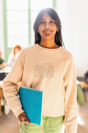 Confident young Indian woman in educational environment holding a notebook - Academic achievement and diversity concept