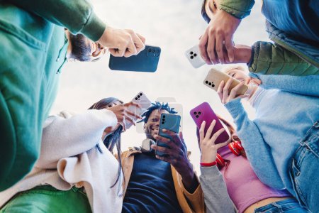 Téléchargez les photos : Groupe de jeunes adultes engagés avec leurs smartphones partageant du contenu - Connectivité sociale et utilisation de la technologie dans le mode de vie moderne - en image libre de droit