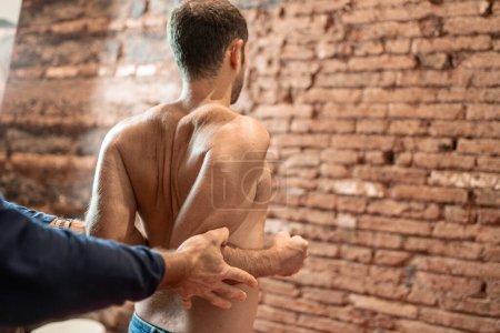 Photo for A physiotherapist conducting a manual therapeutic manipulation on a patient's back, focusing on the spine for alignment and pain relief. - Royalty Free Image