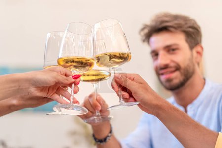A group of friends comes together, raising their glasses of white wine in a toast to celebrate a momentous occasion, embodying the spirit of companionship and good cheer.