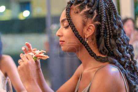 Eine junge Frau verwöhnt die reichen Aromen einer italienischen Gourmet-Pizza, ihr Ausdruck ist ein heiterer Genuss, während sie die frischen, hochwertigen Zutaten genießt, die mit kulinarischer Kompetenz zubereitet werden..