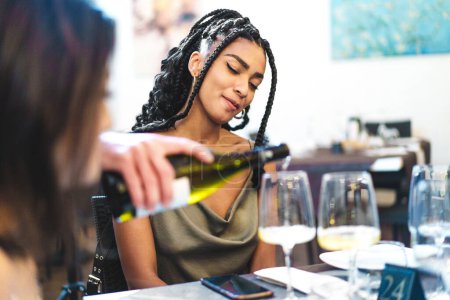 Photo for Smiling woman savoring a wine tasting experience - Indulgence and relaxation at an elegant dinner setting. - Royalty Free Image