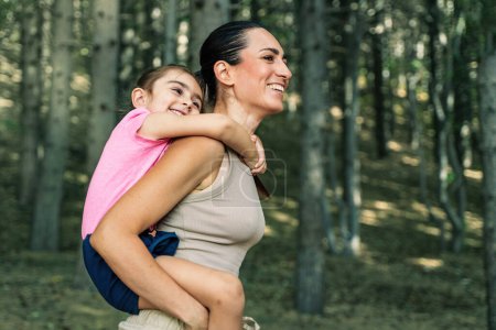 Téléchargez les photos : Mère et fille partagent une étreinte joyeuse lors d'une balade en traîneau dans une forêt ensoleillée, profitant de leur temps en famille ensemble - du temps de qualité en famille à l'extérieur - - en image libre de droit