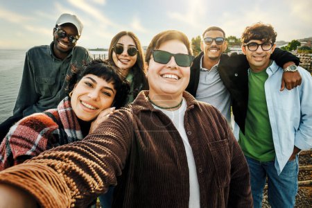 Téléchargez les photos : Divers amis prenant un selfie de groupe à l'extérieur - Sourires et camaraderie au bord de l'eau - Faire place à la diversité et à la joie - en image libre de droit