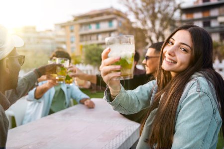 Photo for Multiracial friends clinking glasses in a joyful outdoor gathering - Celebrating moments with fresh drinks - Concept of friendship, diversity, and celebration - Group enjoying drinks outdoors - Royalty Free Image