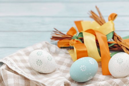 Decoración de Pascua con huevos pintados, cintas de colores en una mesa de madera. Fondo turquesa