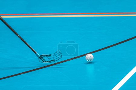 Floorball stick and ball on blue background