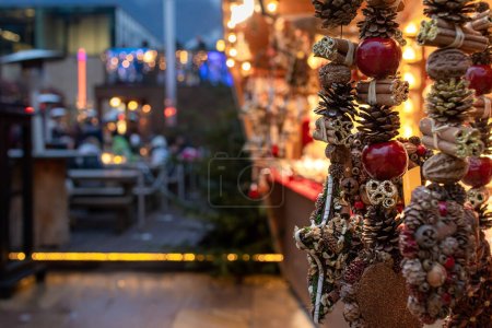 Meran, Südtirol, Italien 02. Dezember 2022 Weihnachtsschmuck und im unscharfen Hintergrund gastronomischer Stand auf dem traditionellen berühmten Markt