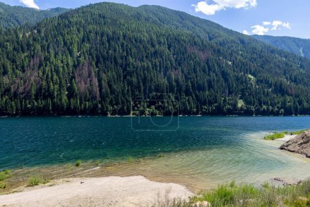 Artificial alpine reservoir lake Zoccolo Zoggler-Stausee and mountain range at Ultental, South Tyrol Italy on sunny summer day. 
