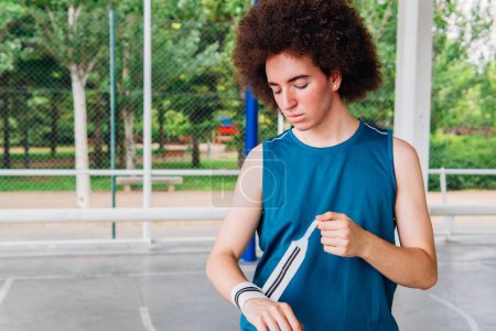 Photo for Basketball player putting on a wristband to protect himself on an urban basketball court - Royalty Free Image