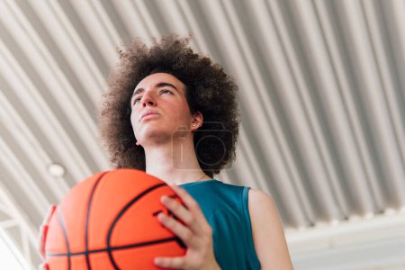 Foto de Retrato de bajo ángulo de un joven jugador de baloncesto en una cancha urbana - Imagen libre de derechos