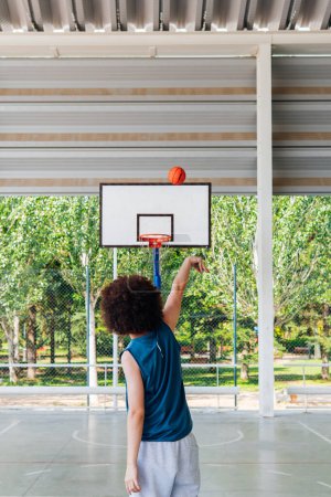 Foto de Foto vertical de la vista trasera de un jugador de baloncesto amateur disparando un tres puntas en una cancha de la ciudad - Imagen libre de derechos