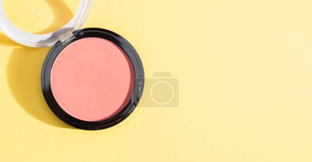 Photo for One tonal powder box for the face with an open transparent cover on the left on a yellow background with copy space on the right, flat lay close-up. Concept isolate cosmetics, beauty salon. - Royalty Free Image