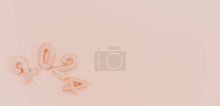 Photo for Shiny candle numbers 2024 lie in a semicircle on the left against a pink background with copy space on the right, flat lay close-up. - Royalty Free Image