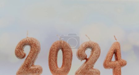 Photo for Shiny candle number 2024 on a blurred pastel blue background with bokeh, side view close-up. - Royalty Free Image