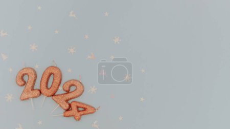 Photo for Shiny light brown candles number 2024 lie with white shiny holiday confetti lie on the left on a pastel blue background with copy space on the right, flat lay close-up. - Royalty Free Image