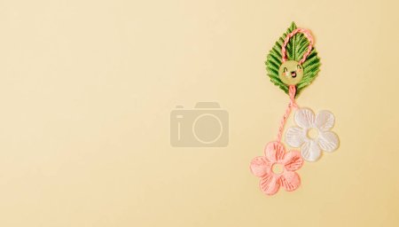 Photo for One beautiful homemade martisor made from flowers, a petal and a cheerful smiley face lies on the right on a gentle yellow background with copy space on the left, flat lay close-up. - Royalty Free Image