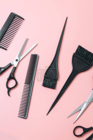 A set of hairdresser's tools from scissors,brushes and combs on a pink background,flat lay closeup. The concept of hairdressing, beauty salon, tools.