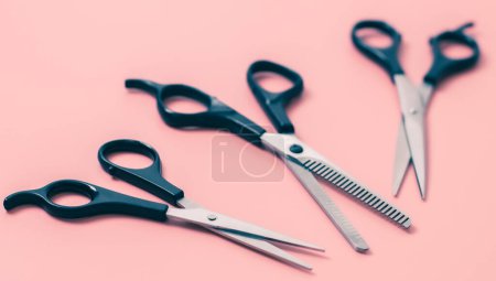 Ensemble de trois paires de ciseaux de coiffeur sur fond rose, vue latérale rapprochée avec profondeur de champ. Le concept de coiffure, salon de beauté, outils.