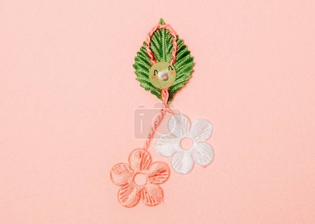 Photo for One beautiful homemade martisor made from flowers, a petal and a cheerful smiley face lies in the center on a pink background, flat lay close-up. - Royalty Free Image