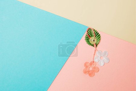 Un hermoso martisor casero hecho de flores, un pétalo y una cara alegre y sonriente se encuentra a la derecha sobre un fondo pastel colorido con espacio de copia a la izquierda, plano de primer plano.