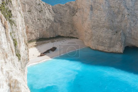 A beautiful view of a deserted beach with a sunken pirate ship washed ashore on a sunny summer day, close-up side view from a cliff.
