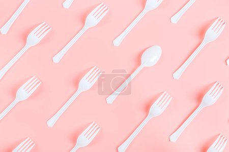Foto de Horquillas de plástico blanco con una cuchara se encuentran en diagonal sobre un fondo rosa, plano de primer plano. Concepto de ecología, plantilla, banner. - Imagen libre de derechos