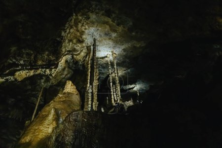 Belle vue sur les stalactites longues et fines naturelles dans une sombre grotte souterraine de Duinen De Haan, Belgique, vue de côté gros plan.