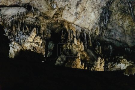 Belle vue latérale de stalactites suspendues et debout complexes naturelles dans une grotte souterraine sombre à De Haan, Belgique.