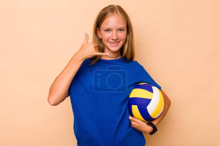 Téléchargez les photos : Petite fille caucasienne jouant au volley isolé sur fond beige montrant un geste d'appel téléphonique mobile avec les doigts. - en image libre de droit