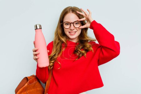 Photo for Young student woman holding a canteen isolated on blue background excited keeping ok gesture on eye. - Royalty Free Image