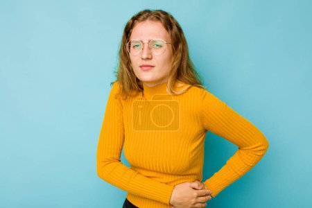 Photo for Young caucasian woman isolated on blue background having a liver pain, stomach ache. - Royalty Free Image