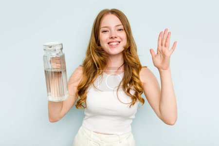 Photo for Young caucasian woman holding jar of water isolated on blue background receiving a pleasant surprise, excited and raising hands. - Royalty Free Image