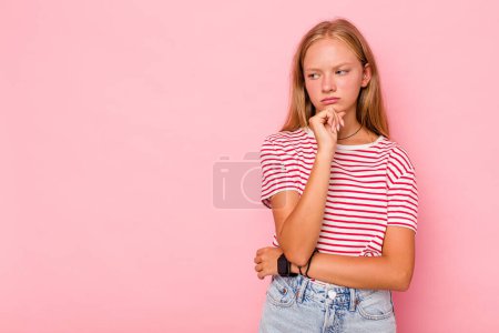 Photo for Caucasian teen girl isolated on pink background looking sideways with doubtful and skeptical expression. - Royalty Free Image