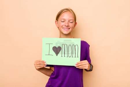 Photo for Little caucasian girl holding I love mom placard isolated on beige background - Royalty Free Image