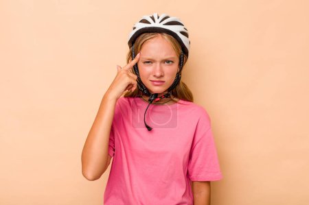 Téléchargez les photos : Petite fille caucasienne portant un casque de vélo isolé sur fond beige montrant un geste de déception avec index. - en image libre de droit