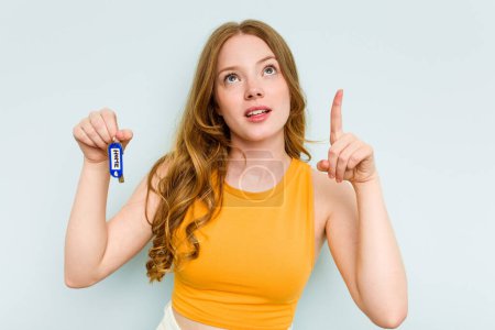 Téléchargez les photos : Young caucasian woman holding home keys isolated on blue background pointing upside with opened mouth. - en image libre de droit