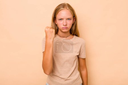Foto de Caucásico adolescente chica aislado en beige fondo mostrando puño a cámara, agresiva expresión facial. - Imagen libre de derechos