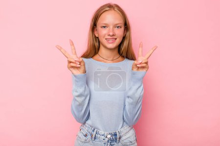 Photo for Caucasian teen girl isolated on pink background showing victory sign and smiling broadly. - Royalty Free Image