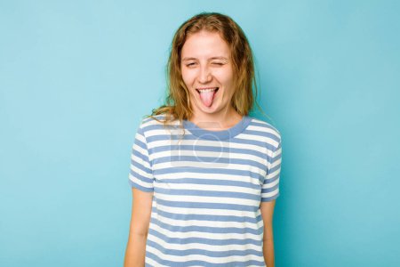 Photo for Young caucasian woman isolated on blue background funny and friendly sticking out tongue. - Royalty Free Image