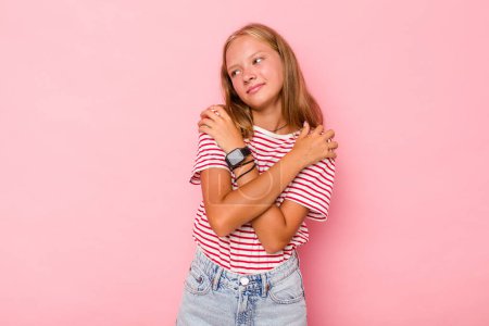 Foto de Caucásico adolescente chica aislado en rosa fondo abrazos, sonriendo despreocupado y feliz. - Imagen libre de derechos