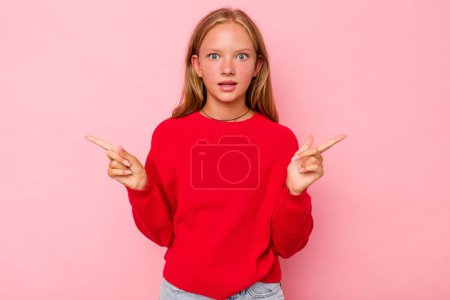 Photo for Caucasian teen girl isolated on pink background pointing to different copy spaces, choosing one of them, showing with finger. - Royalty Free Image